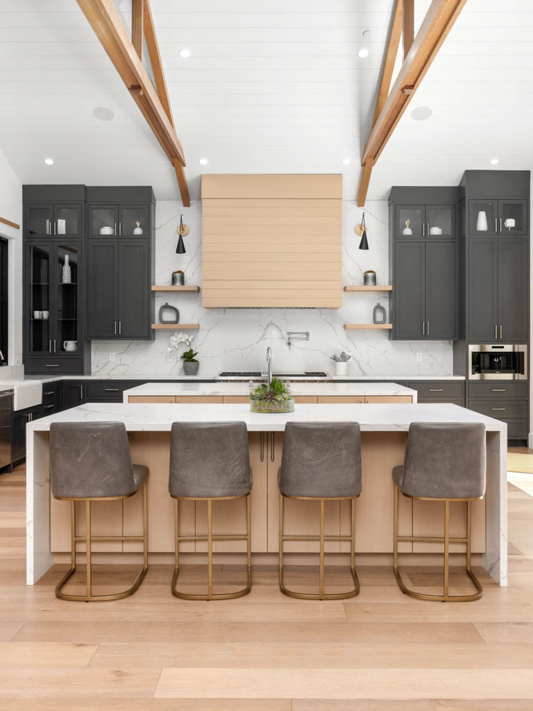 a large kitchen area with a counter and three stools